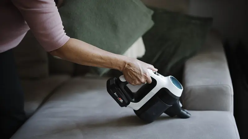 Teppichreinigung Uster: Stoffsofa wird mit einem Handsauger abgesaugt